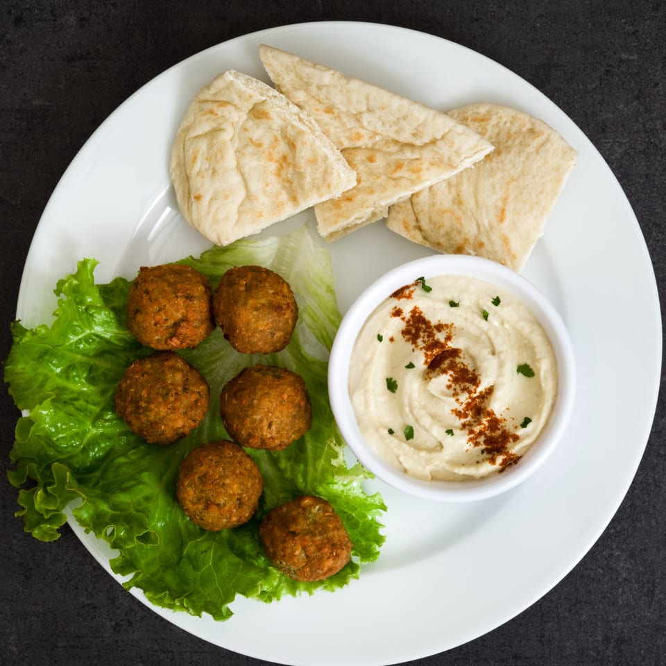 Mediterranean falafel, hummus, and pita bread on a white plate.